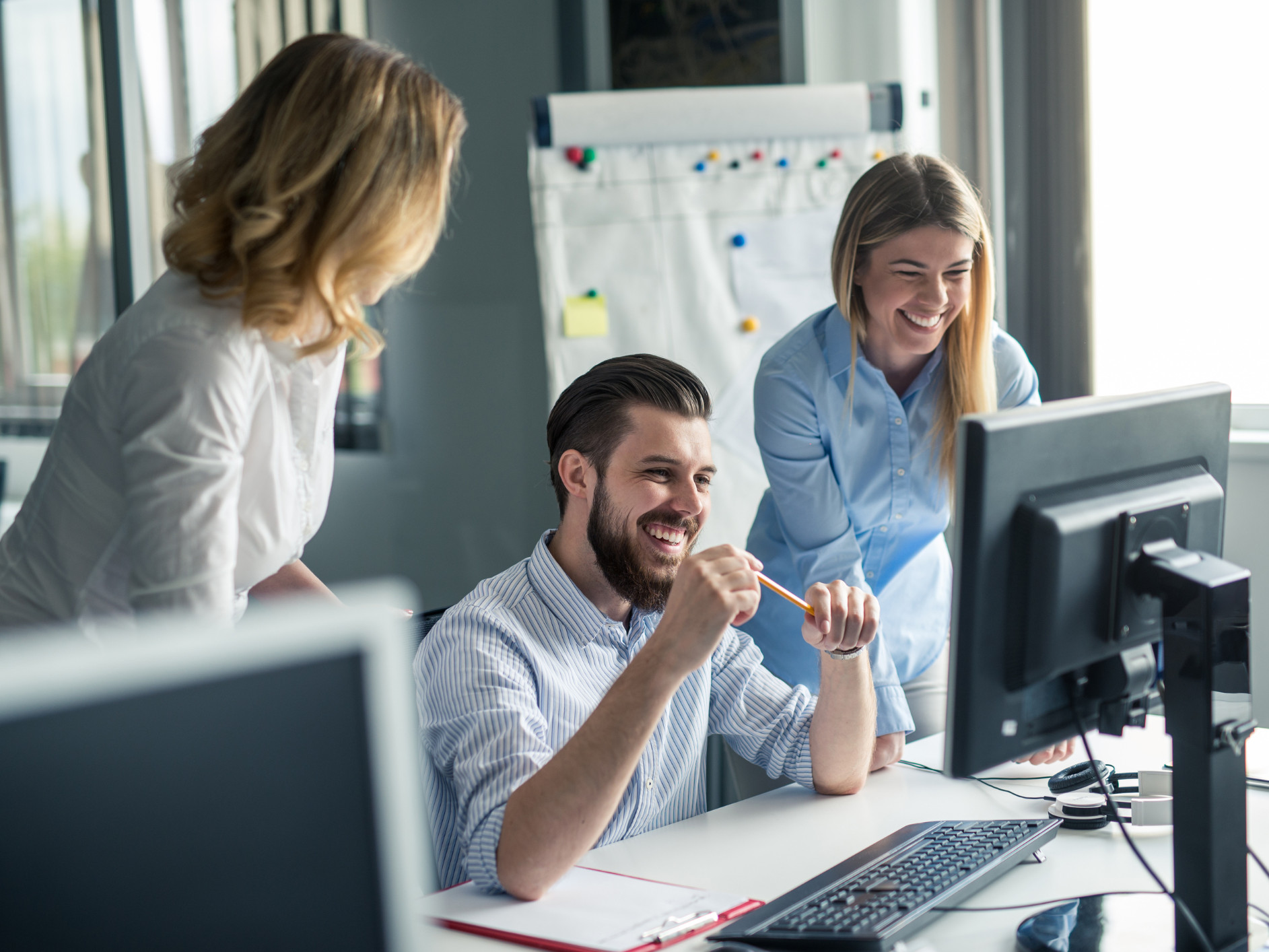 Zwei Frauen und ein Mann schauen auf einen Computerbildschirm