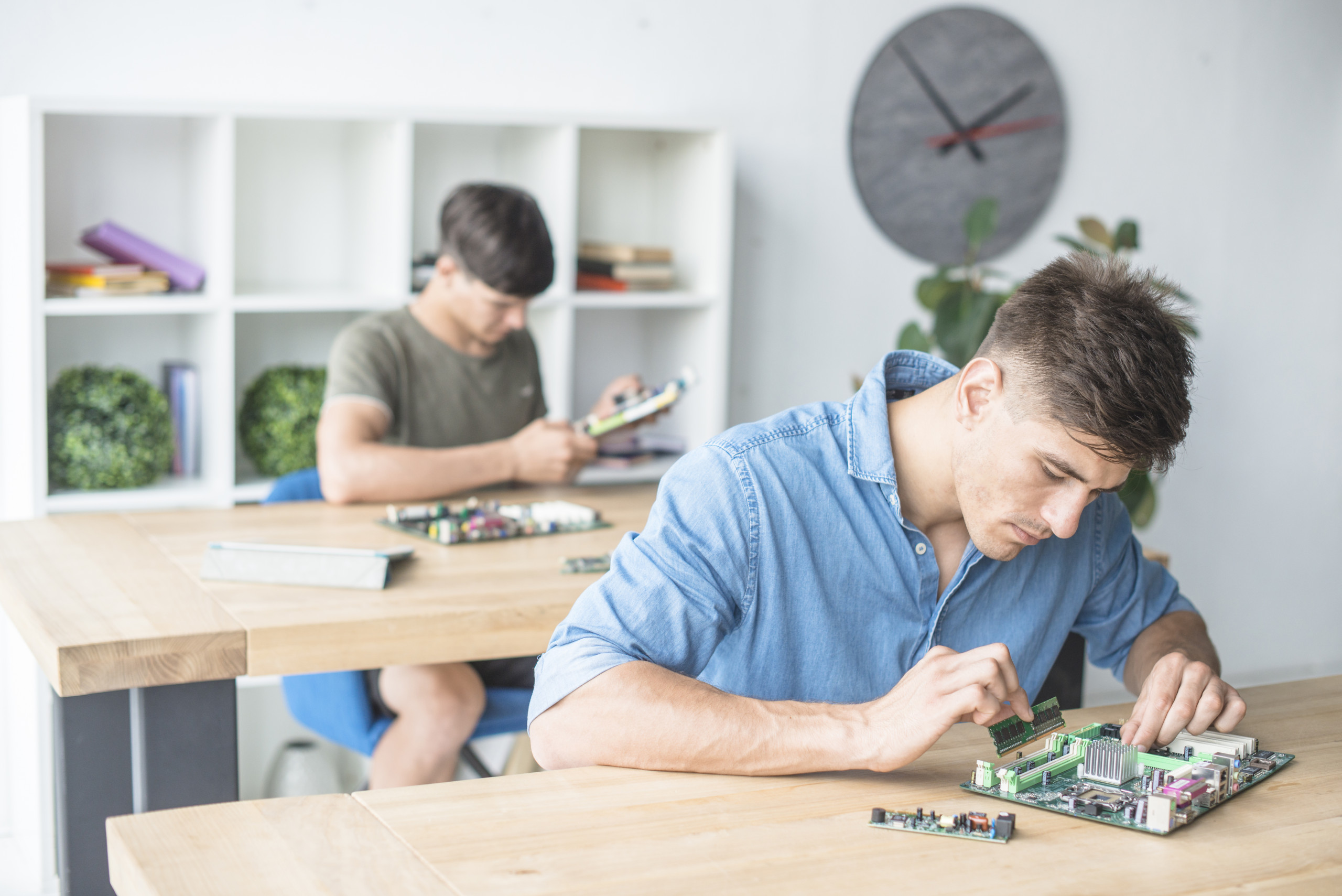 Zwei junge Männer arbeiten mit Computerteilen