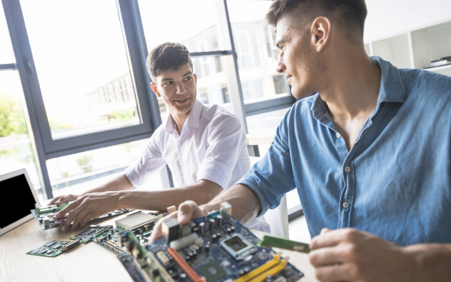 Zwei junge Männer reparieren Elektroteile eines Computers