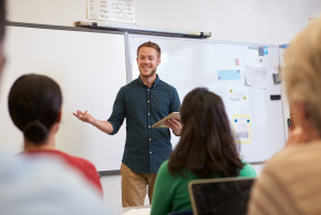 Symbolbild Lehrer in Klassenraum vor Schüler:innen.