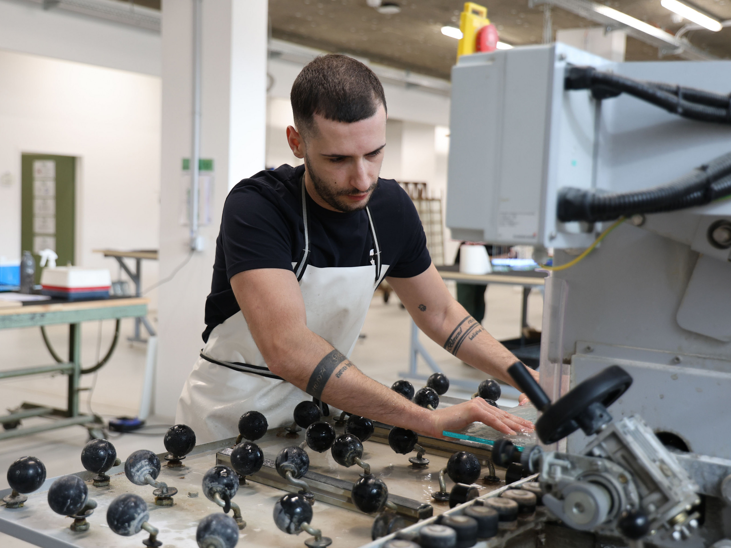 Ein junger Mann, der an einer Glasschneidemaschine arbeitet