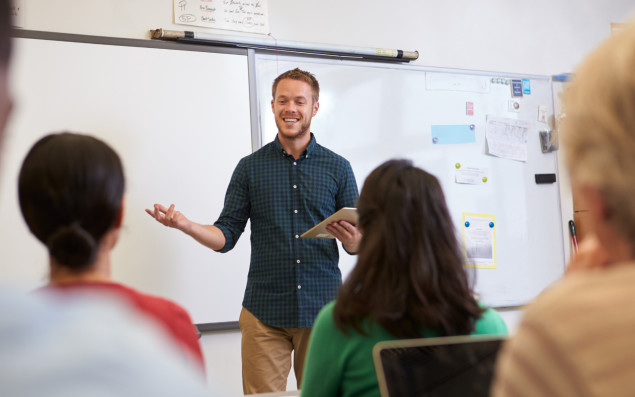 Ein Lehrer steht vor einer Klasse und unterrichtet.